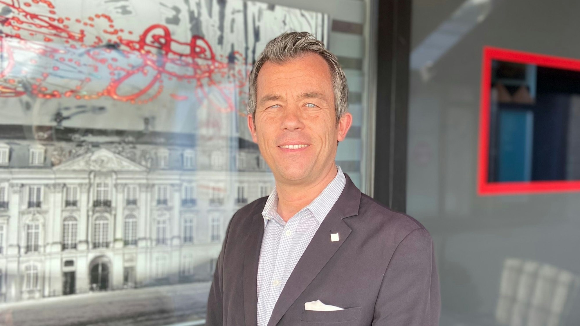 Auf dem Bild ist das Portrait eines Mannes im Sakko zu sehen.