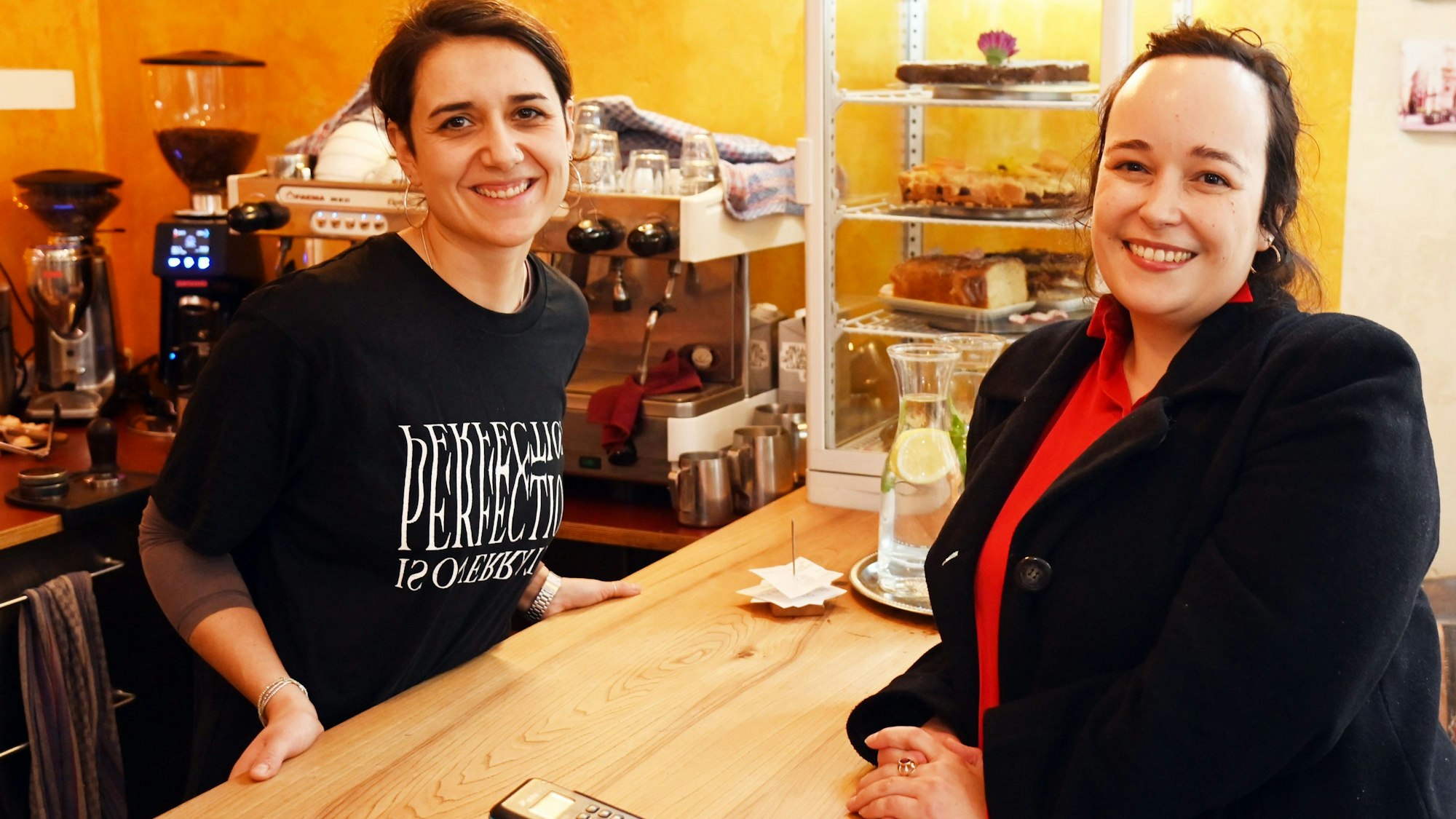 Zwei Frauen stehen sich an der Theke eines Cafés gegenüber.