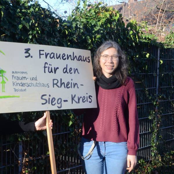 Zwei Frauen mit einem Schild. 3. Frauenhaus für den Rhein-Sieg-Kreis steht darauf.