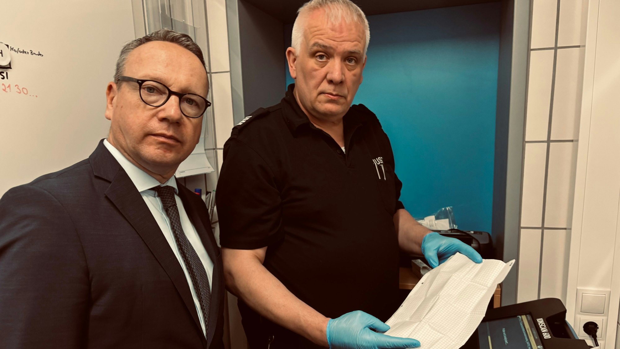NRW-Justizminister Benjamin Limbach (Grüne) und der JVA-Bedienstete Peter Schönenberg vor dem neuen Drogenscanner der JVA Rheinbach.