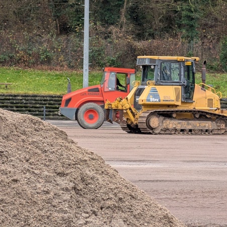 Das Foto zeigt Bagger und einen Sandhaufen auf dem Sportplatz in Berrenrath.