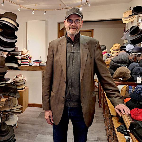 Paul Pauli steht in seinem Geschäft zwischen Regalen voller Hüte und Mützen.
