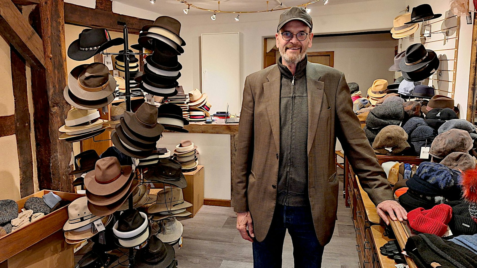 Paul Pauli steht in seinem Geschäft zwischen Regalen voller Hüte und Mützen.
