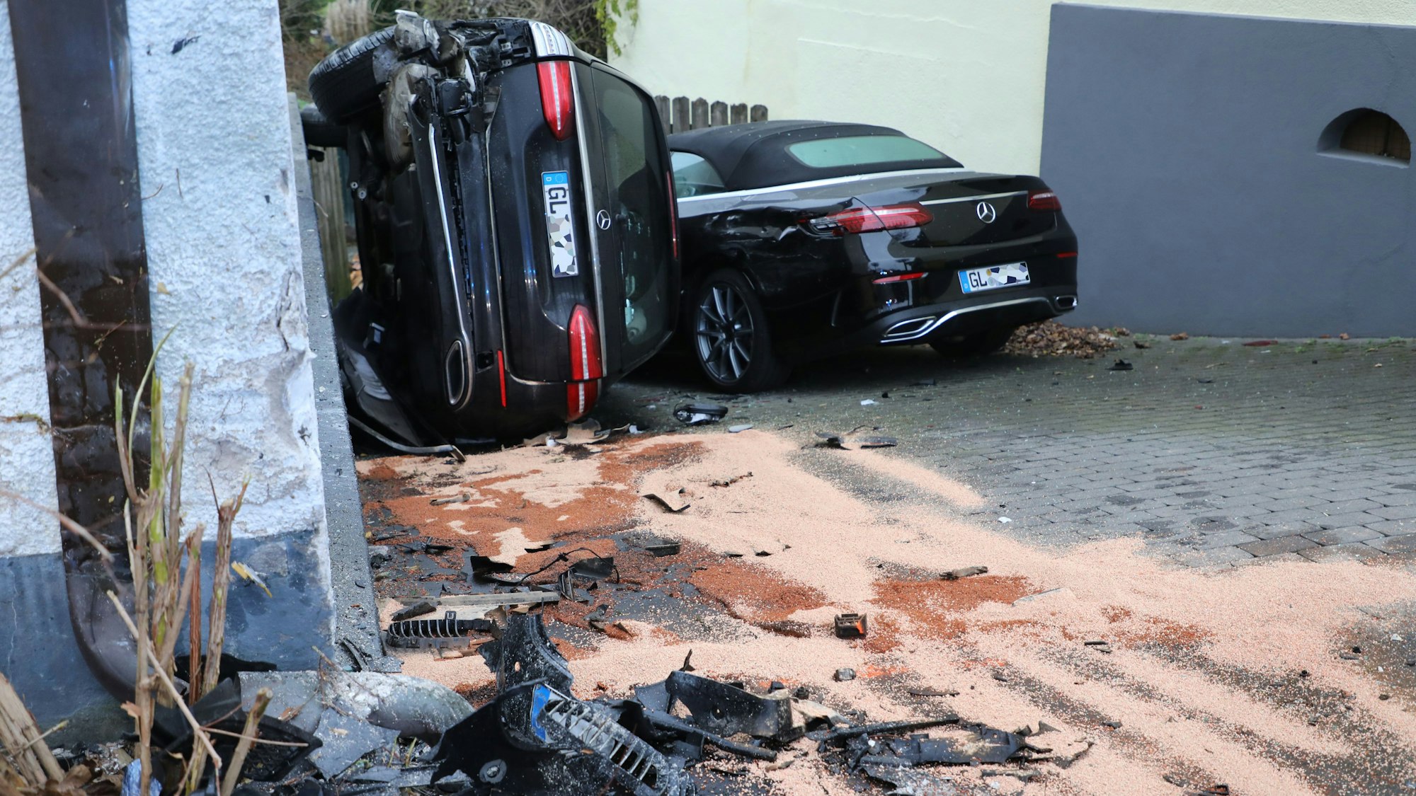 Zwei total demolierte Autos stehen an einer Hauswand.