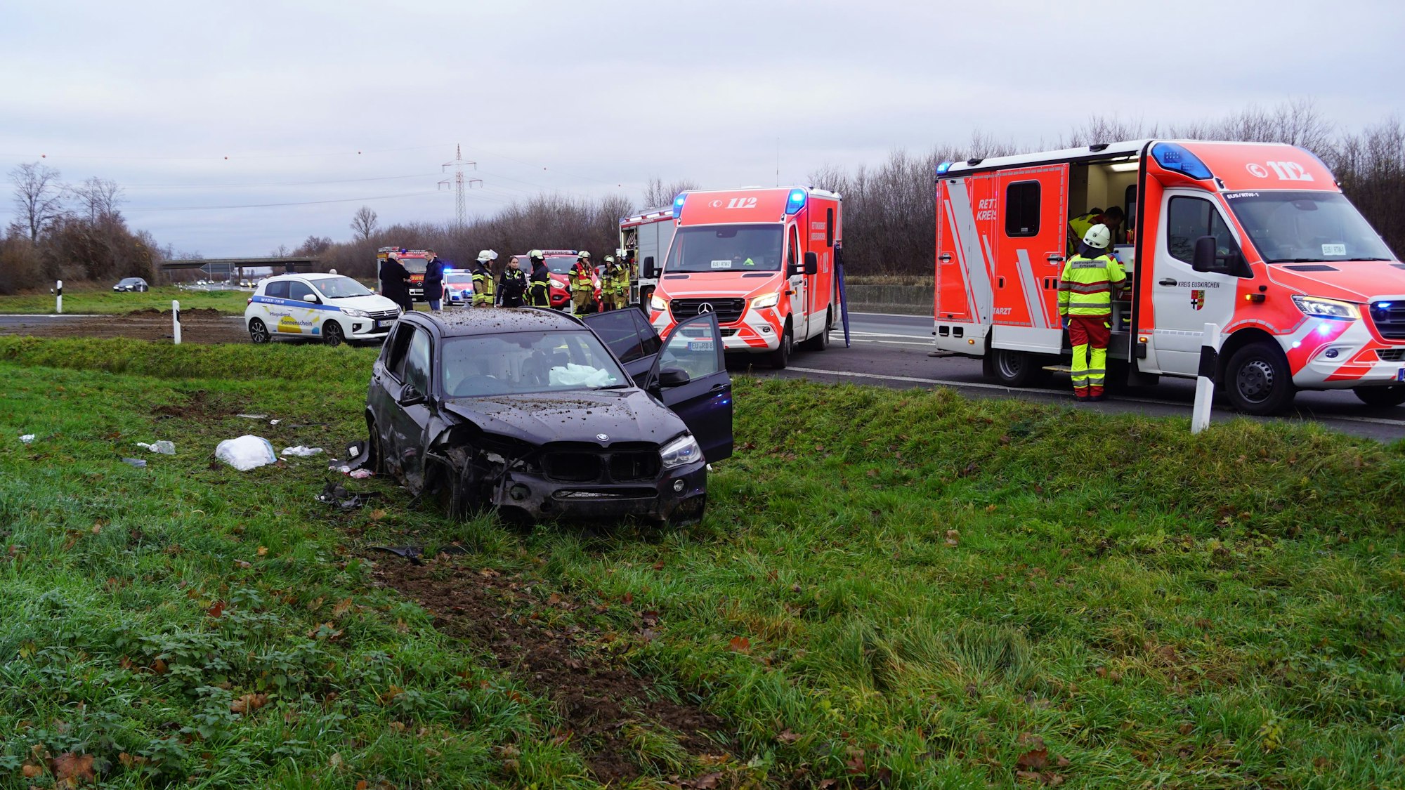 Der verunglückte Wagen steht auf dem Grünstreifen. Auf der Autobahn stehen die Fahrzeuge des Rettungsdienstes.
