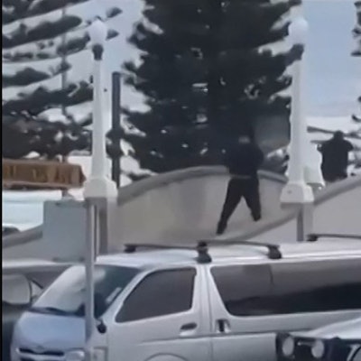 TOPSHOT - This screen grab made from UGC handout video footage courtesy of Timothy Brant-Coles shows two gunmen dressed in black firing multiple shots on a bridge at Bondi Beach in Sydney on December 14, 2025. Australian police said two people were in custody following reports of multiple gunshots on December 14 at Sydney's famed Bondi Beach, urging the public to take shelter. (Photo by Handout / various sources / AFP) / RESTRICTED TO EDITORIAL USE - MANDATORY CREDIT „AFP PHOTO / COURTESY OF TIMOTHY BRANT-COLES“