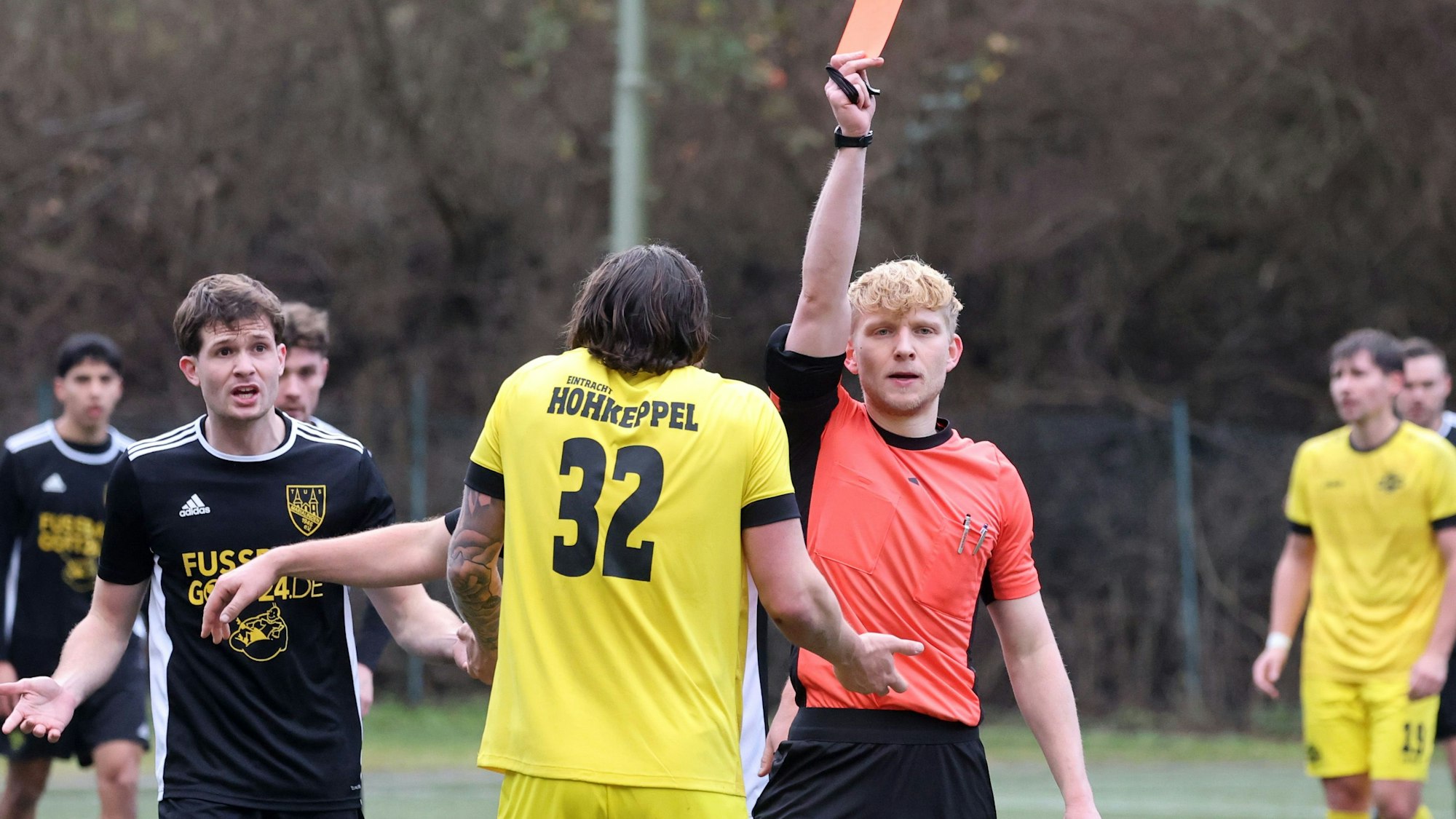 Ein Schiedsrichter zeigt einem Fußballer die gelb-rote Karte.
