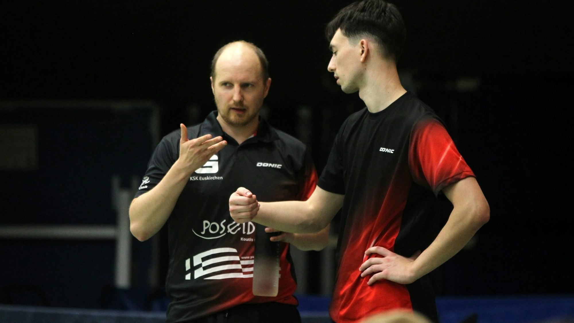 Zwei Spieler des TTC Vernich stehen nebeneinander und sprechen miteinander. Einer hält eine Trinkflasche in der Hand.