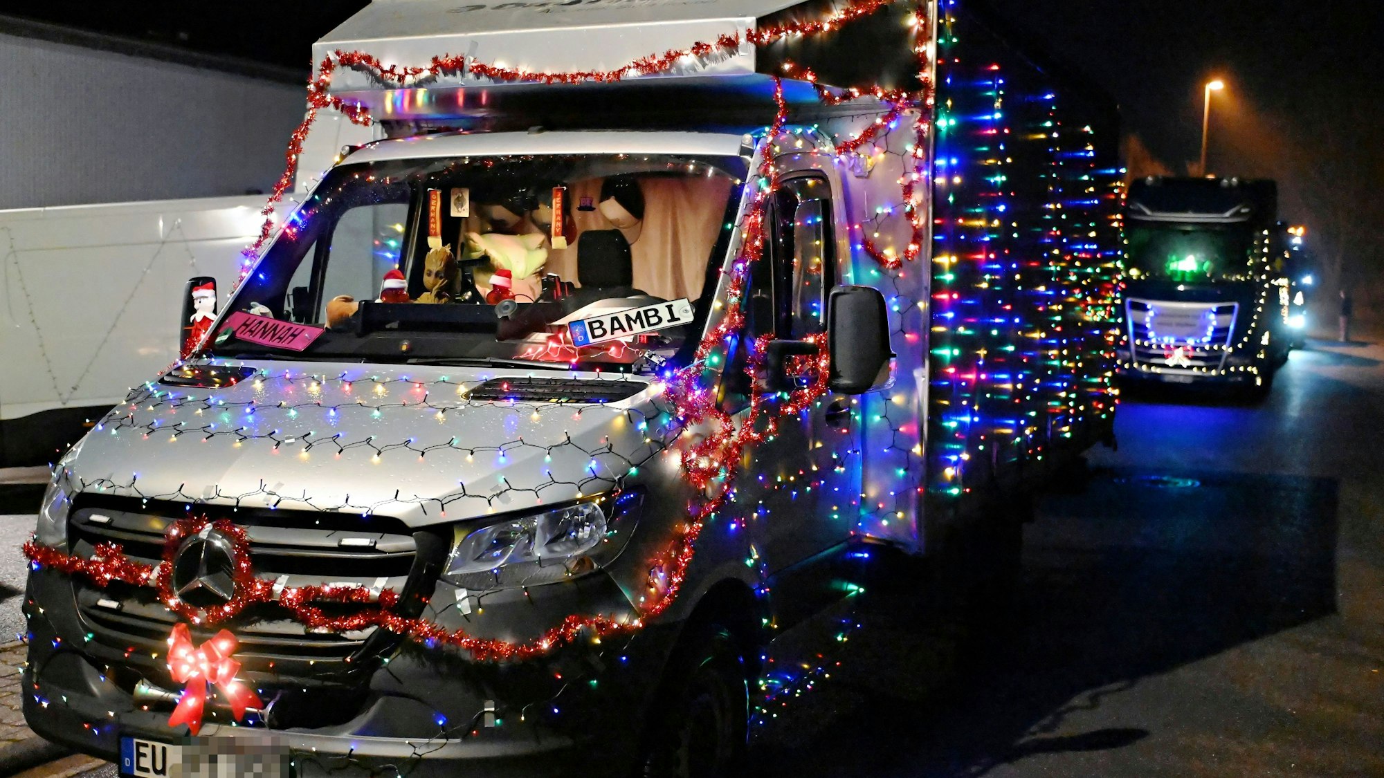 Ein silberner Kleinlastwagen ist über und über mit bunten Lichterketten verziert. An der Windschutzscheibe hängt ein Schild mit der Aufschrift „Bambi“.