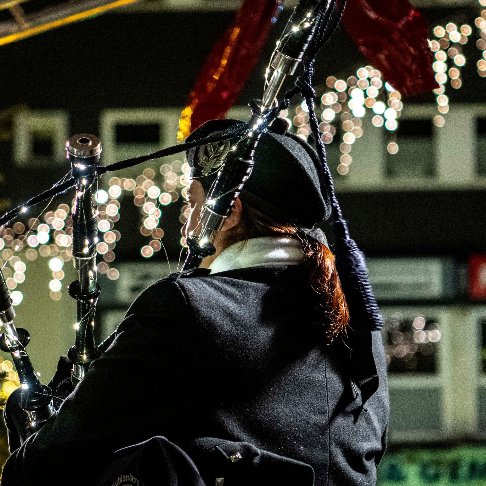 Ein Dudelsackspieler hat sein Instrument mit einer Lichterkette geschmückt.