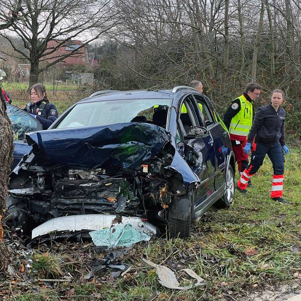 Polizeibeamte und Helfer des Rettungsdienstes an der Unfallstelle hinter dem im Frontbereich total zerstörten Fahrzeug.
