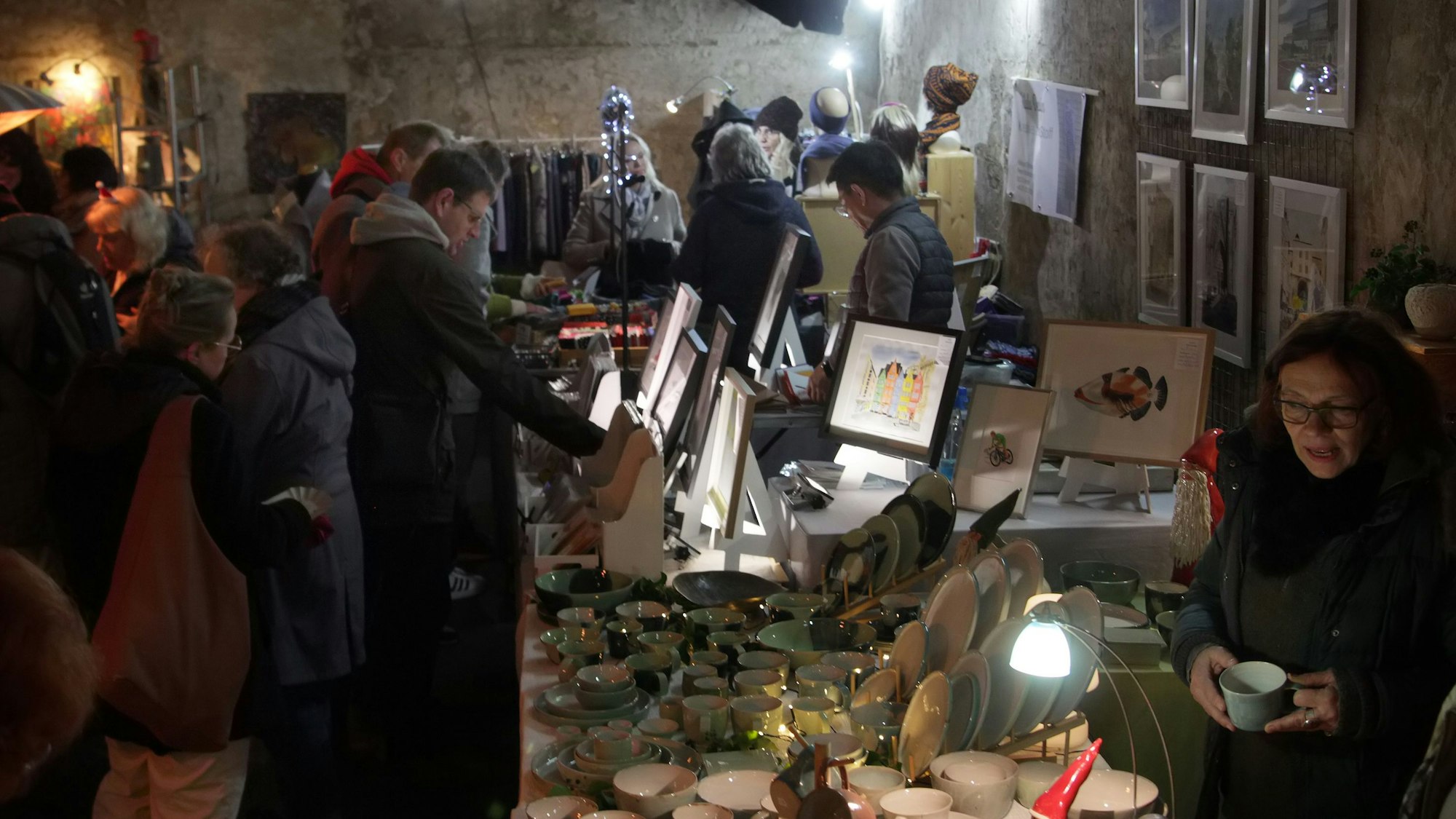 Das Foto zeigt Menschen, die Kunsthandwerk auf einem Weihnachtsmarkt begutachten.