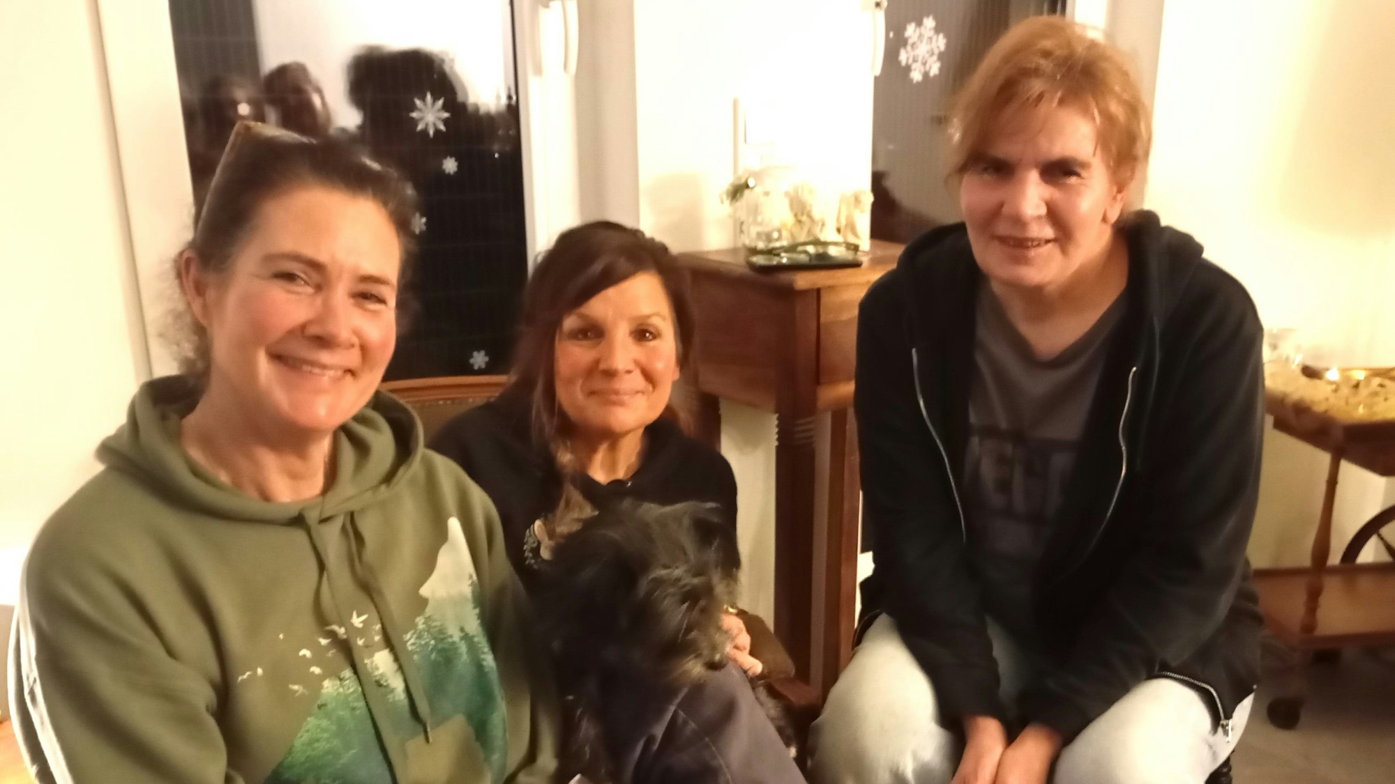 Das Foto zeigt die drei Frauen, eine mit einem Hund auf dem Schoß.