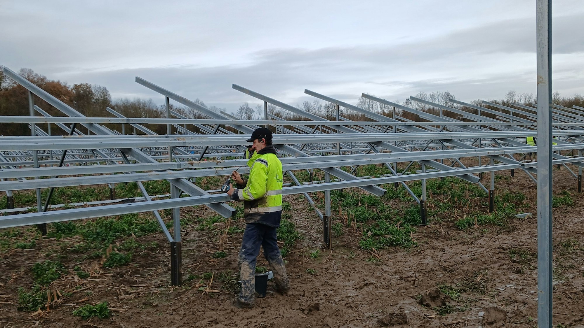 Das Foto zeigt einen Mann, der am Gerüst einer Solaranlage arbeitet.