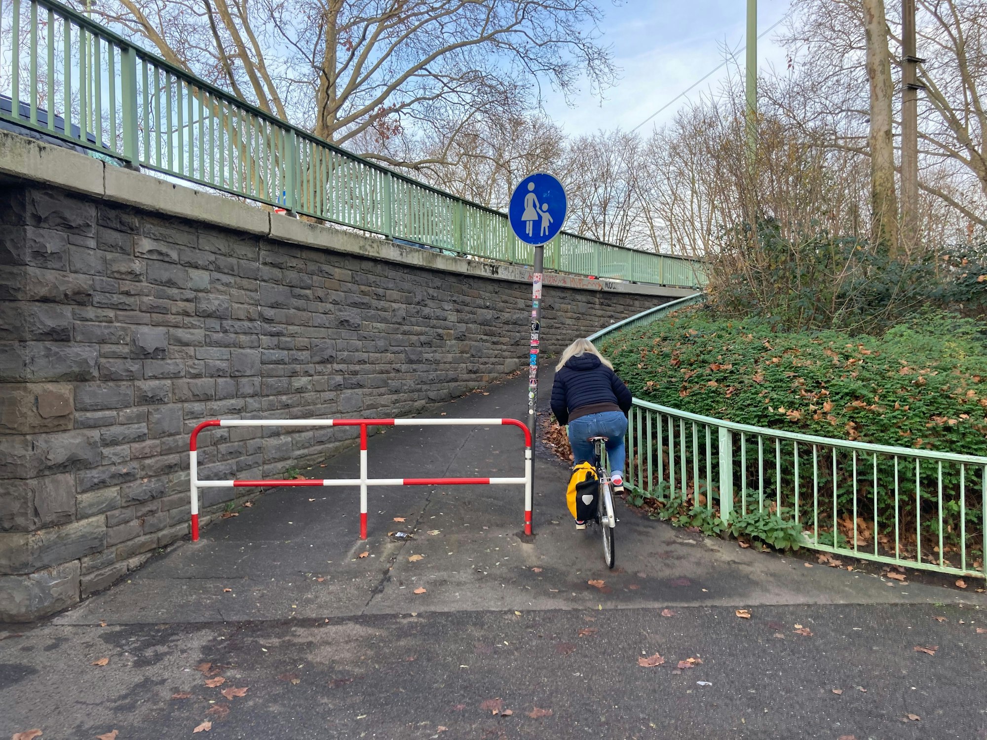 Die linksrheinische, auf der südlichen Seite gelegene Rampe mit erneuertem Drängelgitter und einem Verkehrsschild „Sonderweg Fußgänger“.