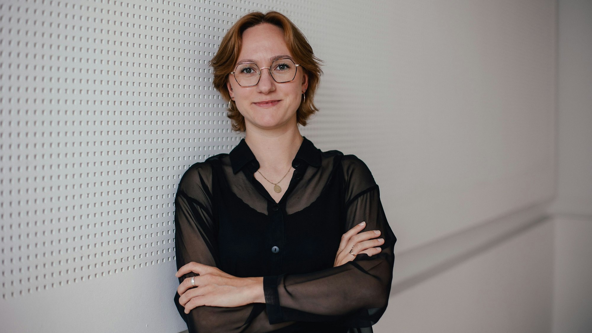 Eine Frau schaut mit verschränkten Armen in die Kamera.