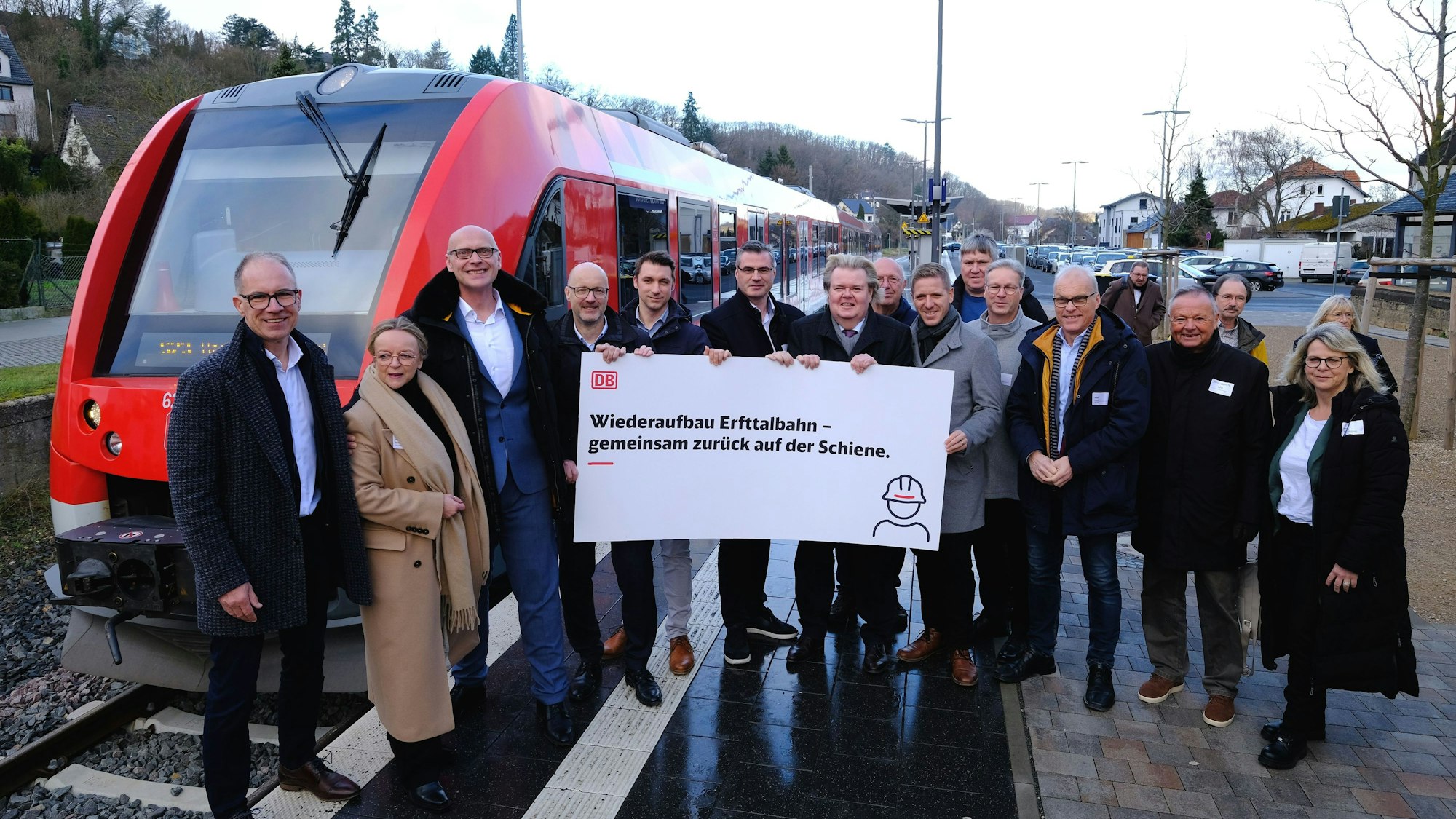 Das Foto zeigt eine Gruppe von rund 20 Personen, die mit einem Plakat vor einem Nahverkehrszug am Bahnsteig in Bad Münstereifel stehen.