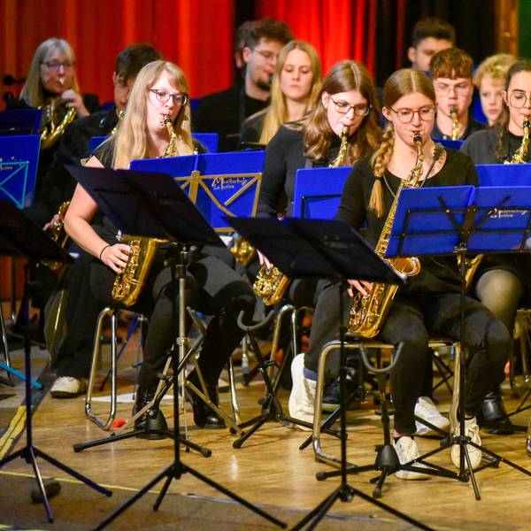 Das Bild zeigt junge Musikschüler mit Blasinstrumenten, vor ihnen stehen Notenständer.