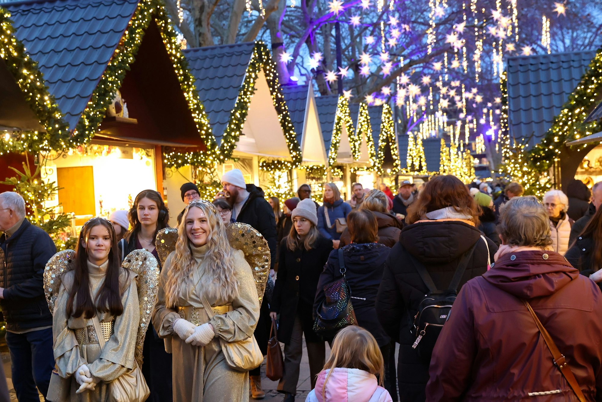 Zwei als Engel verkleidete Frauen stehen auf dem Weihnachtsmarkt auf dem Neumarkt.