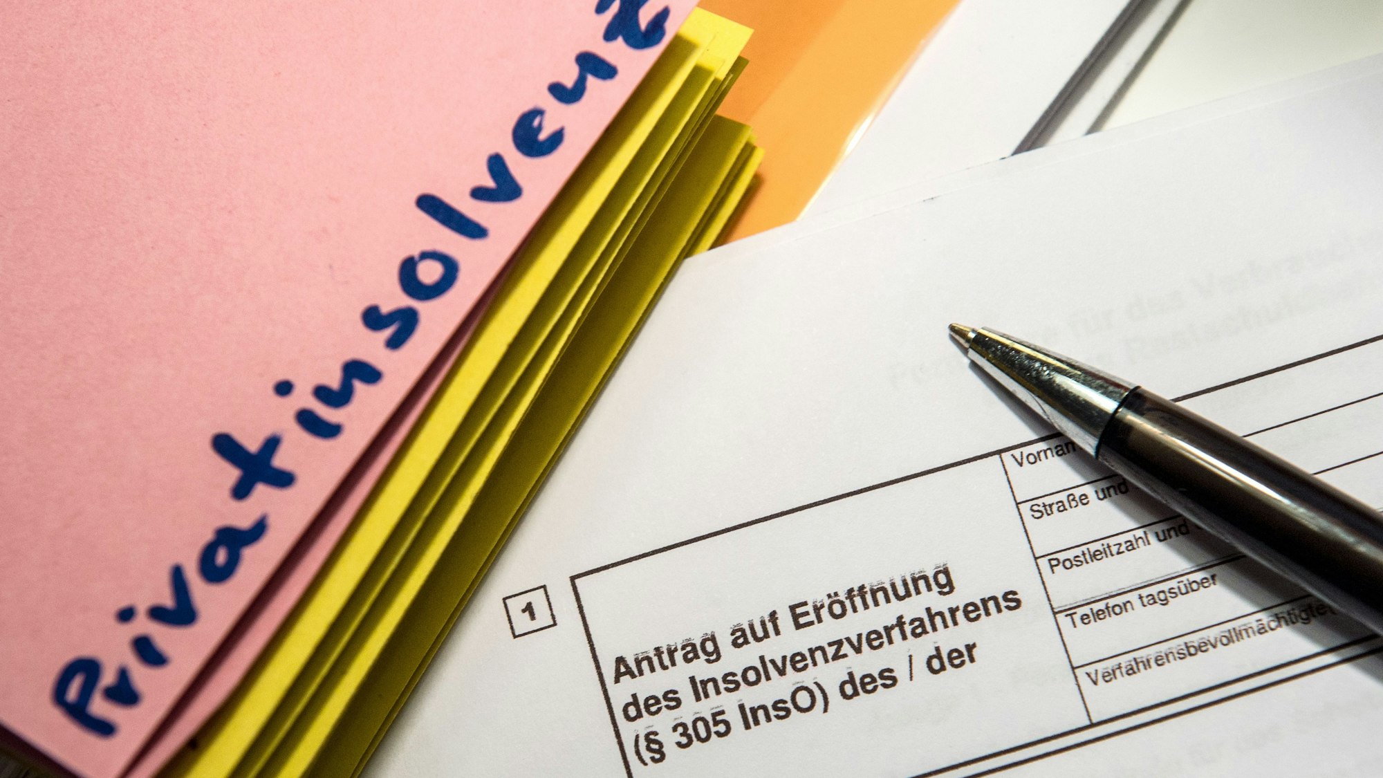 Das Wort „Privatinsolvenz“ steht auf einem Trennblatt, während davor ein Antrag zur Eröfnung eines Insolvenzverfahrens liegt.