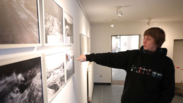 Eine Frau zeigt auf historische Fotos.