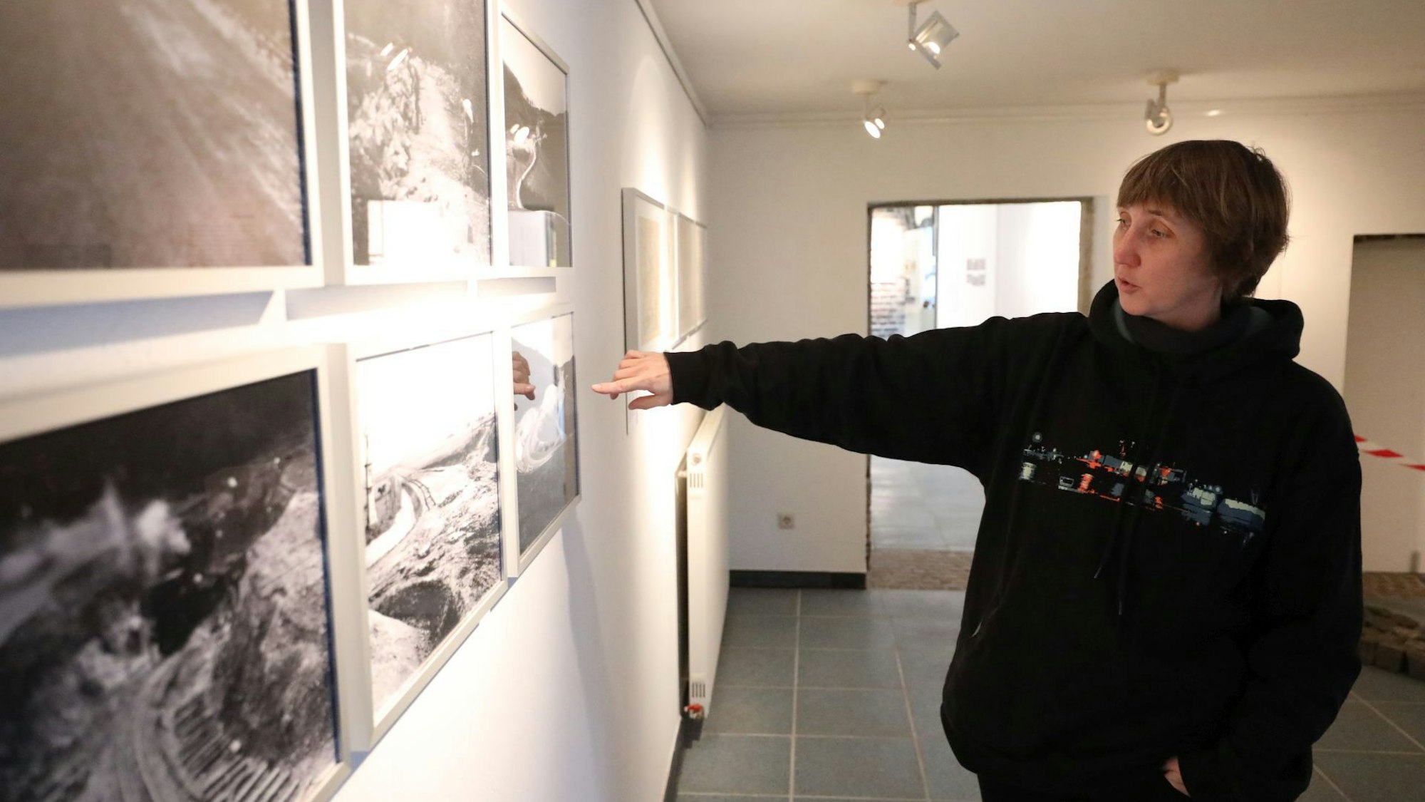 Eine Frau zeigt auf historische Fotos.