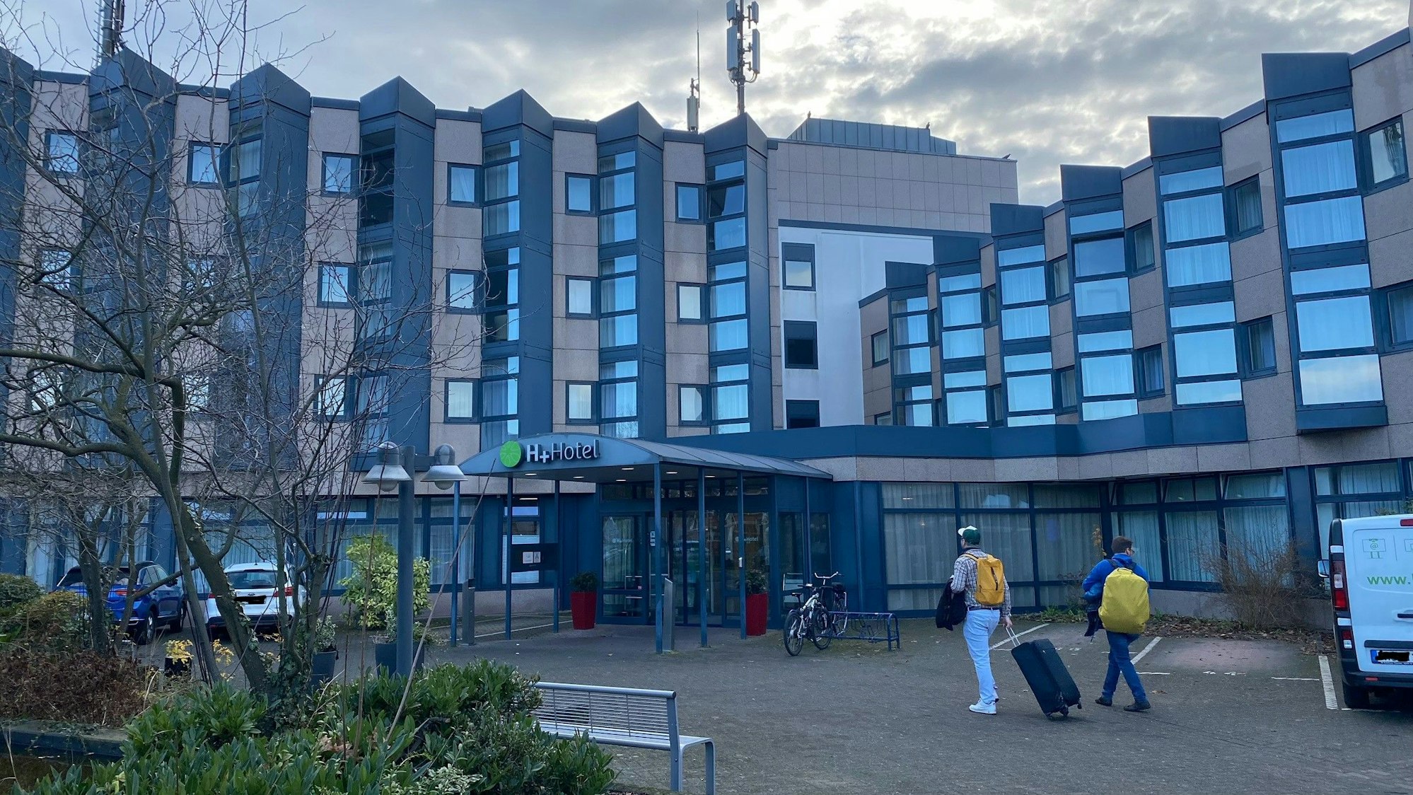 Zu sehen sind ein Brühler Hotel sowie zwei Gäste auf dem Weg zu dessen Eingang.