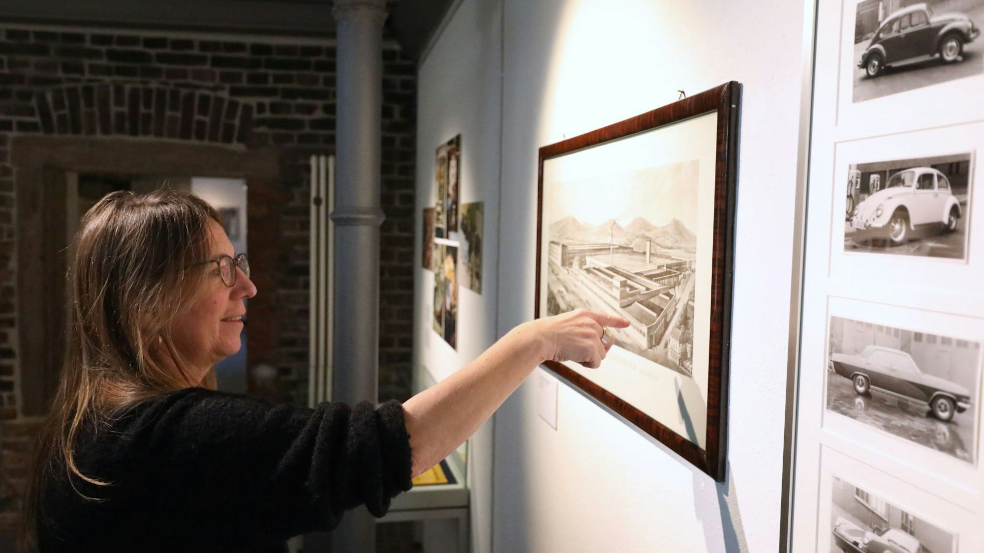 Eine Frau zeigt auf die Darstellung eines Fabrikgebäudes.