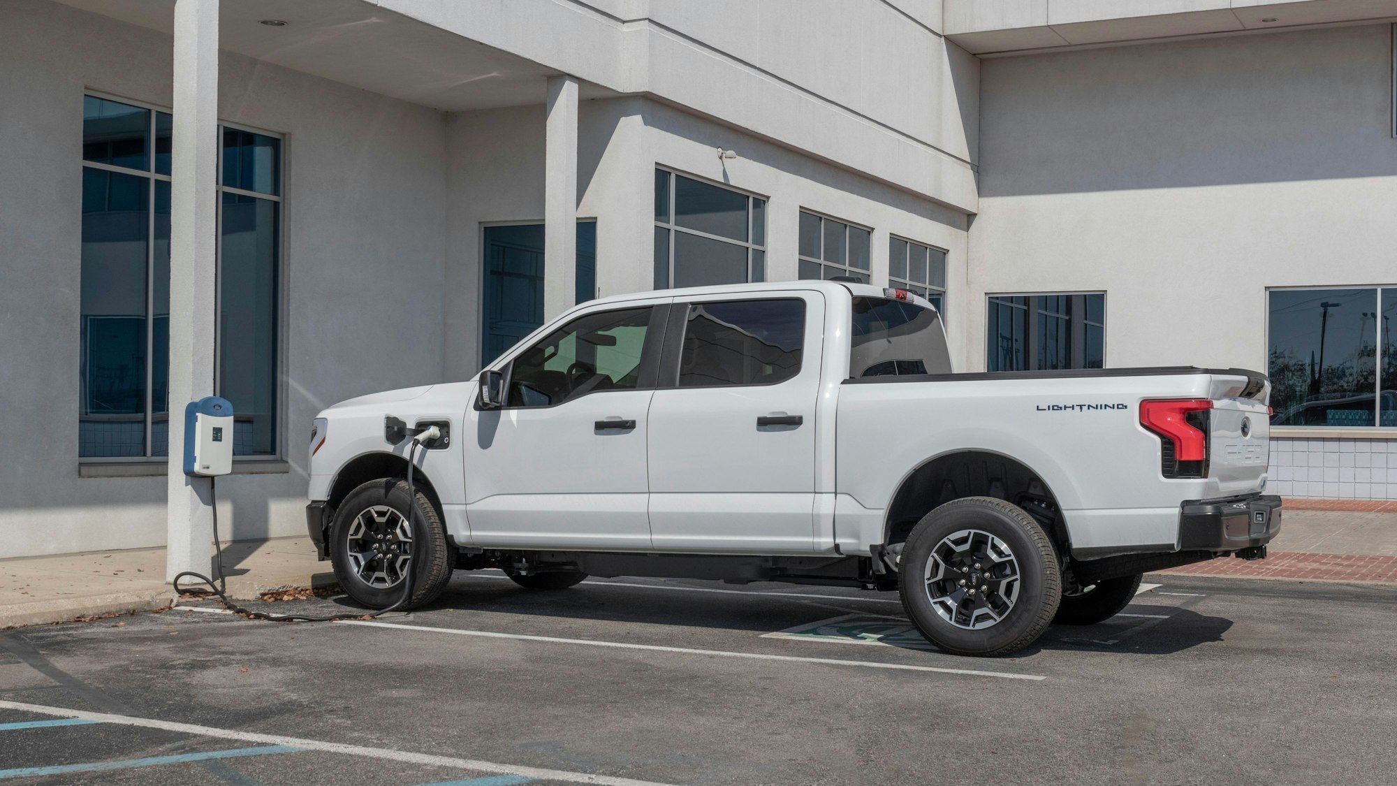 Ein weißer Ford F150 Lightning lädt an einer Ladesäule.
