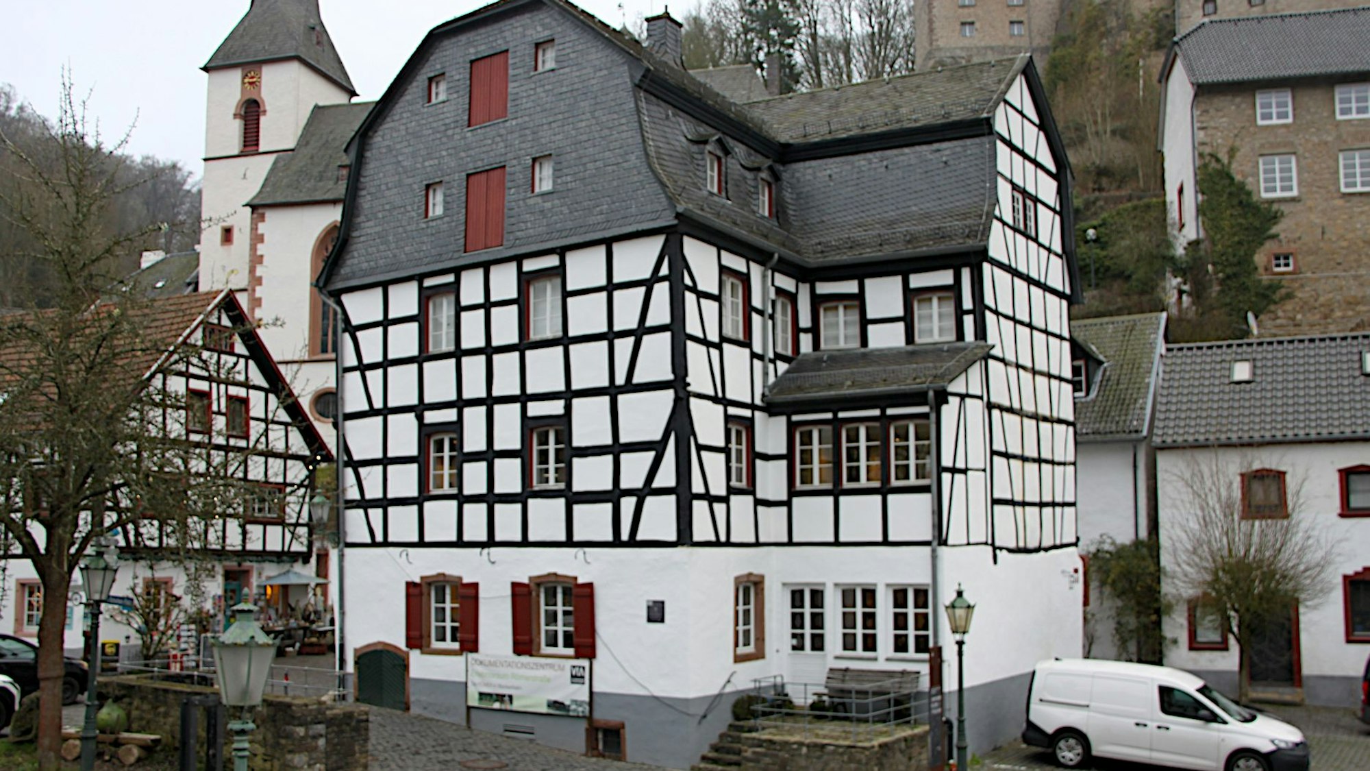 Beim Gildehaus handelt es sich um ein mehrstöckiges Fachwerkgebäude im Ortszentrum von Blankenheim. Im Hintergrund ist die Kirche zu sehen.