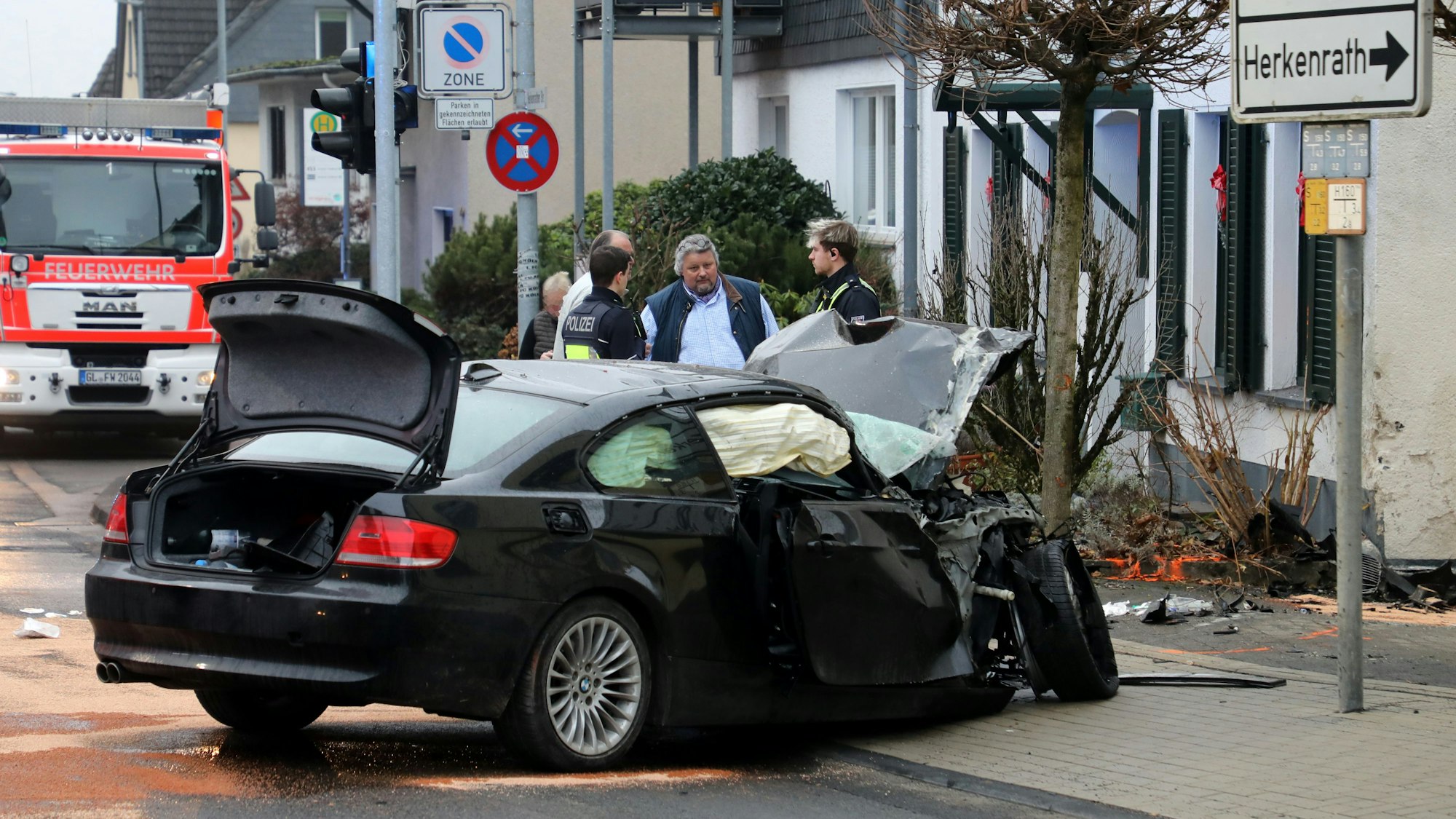 Thomas Cüpper steht mit Polizeibeamten am Auto eines Unfallfahrer am Samstag (13.12.) vor seinem Wohnhaus in Bergisch Gladbach-Sand.