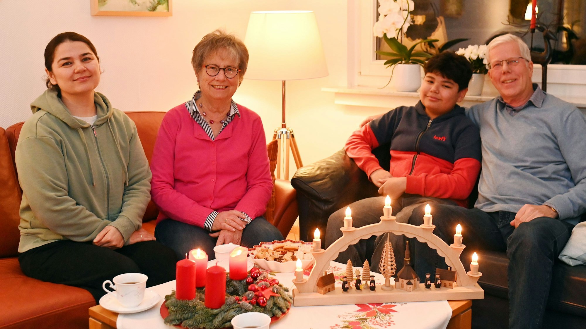 Habiba, Sino, Karin und Wilfried Kiel sitzen im Wohnzimmer. Der Tisch ist adventlich gedeckt und geschmückt.