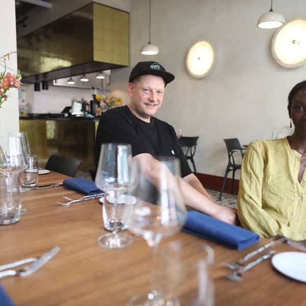 Die Restaurantbetreiber, ein Mann und eine Frau, sitzen am gedeckten Tisch.