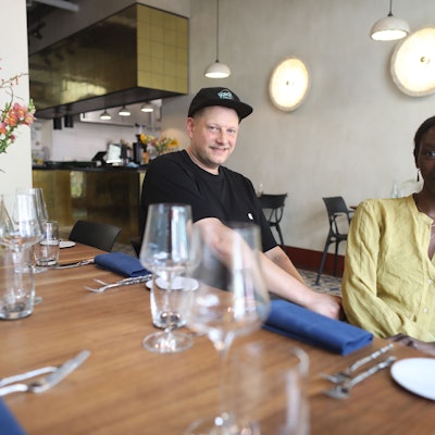 Die Restaurantbetreiber, ein Mann und eine Frau, sitzen am gedeckten Tisch.