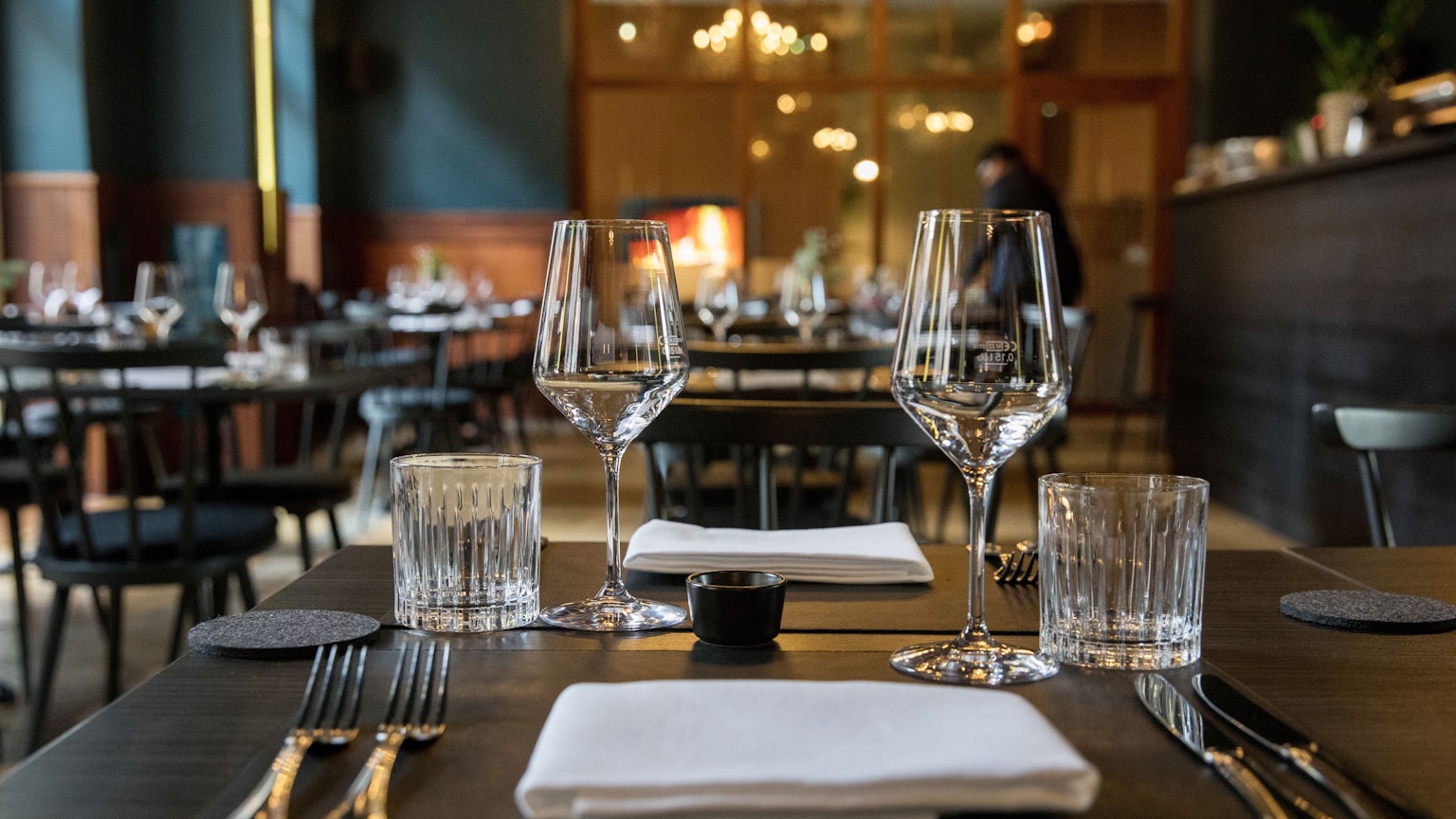 Ein Blick ins Restaurant Augustin mit blauen Wänden, dunklen Stühlen, Holztischen und vielen Lampen an der Decke.