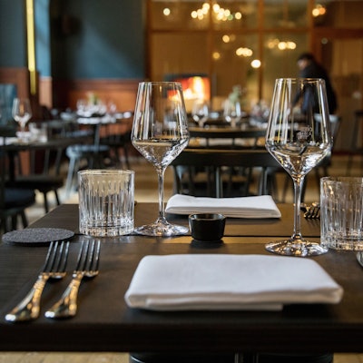 Ein Blick ins Restaurant Augustin mit blauen Wänden, dunklen Stühlen, Holztischen und vielen Lampen an der Decke.