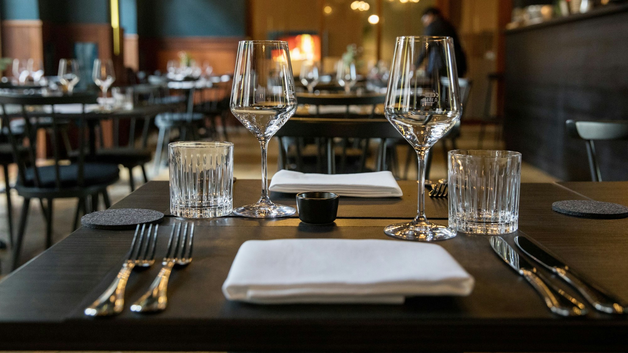 Ein Blick ins Restaurant Augustin mit blauen Wänden, dunklen Stühlen, Holztischen und vielen Lampen an der Decke.