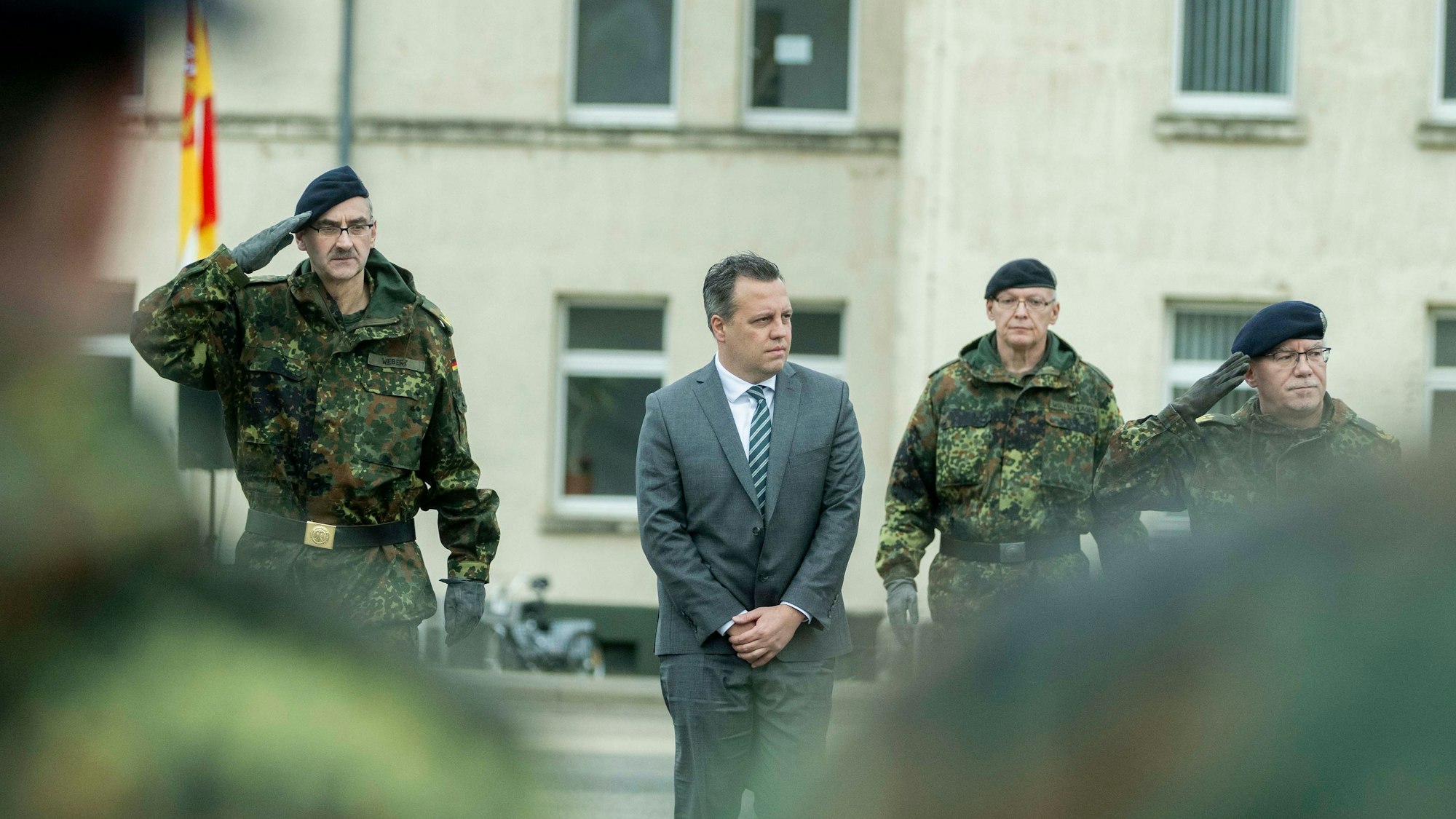 Drei Bundeswehrsoldaten und ein Zivilist stehen in einer Reihe auf dem Hof der Kaserne in Euskirchen.