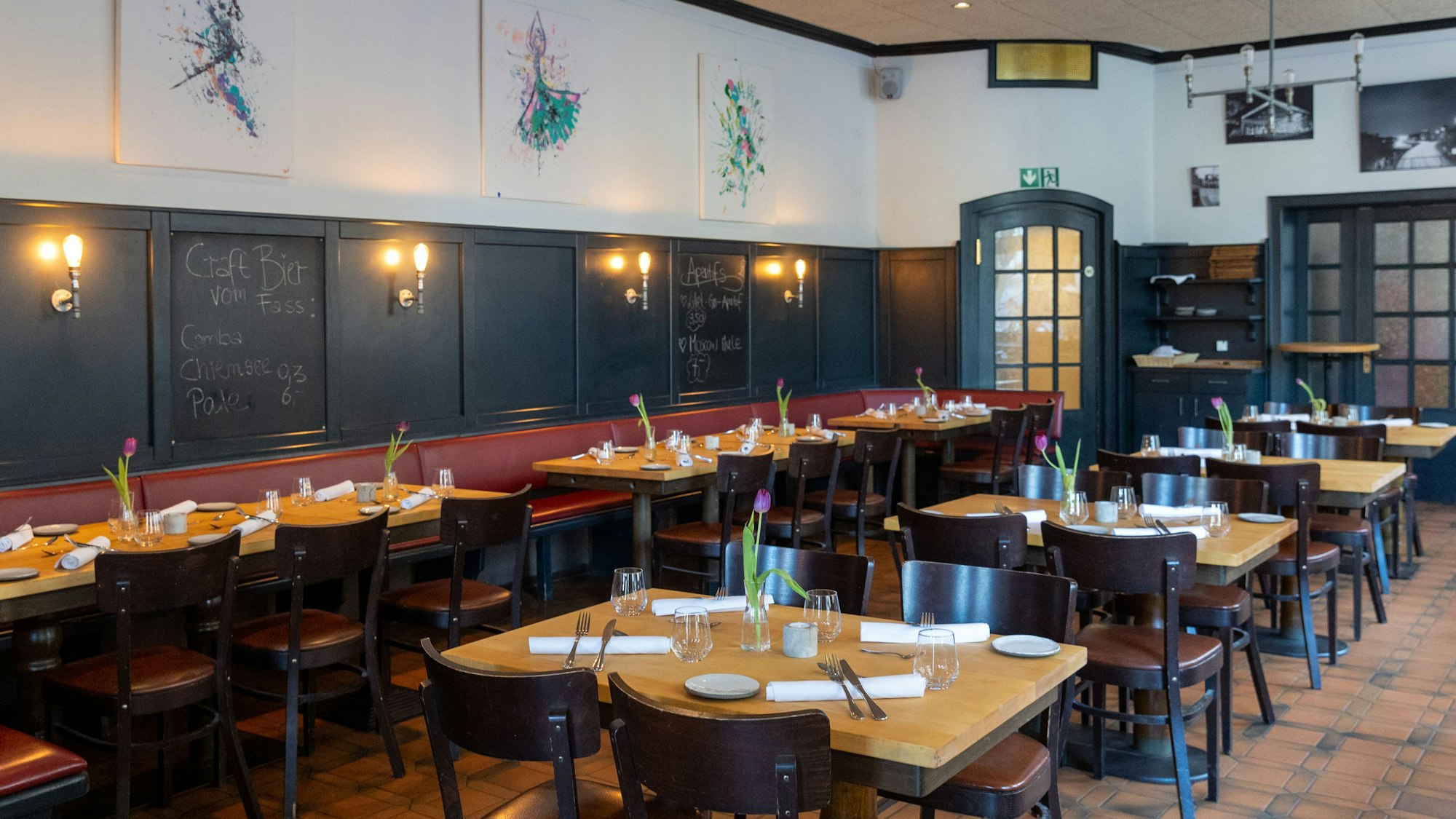 Gedeckte Tische stehen in einem Gastraum.