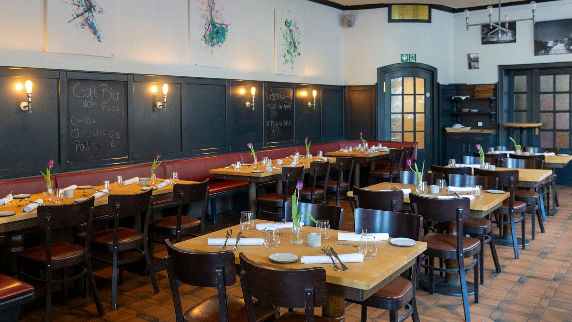 Gedeckte Tische stehen in einem Gastraum.
