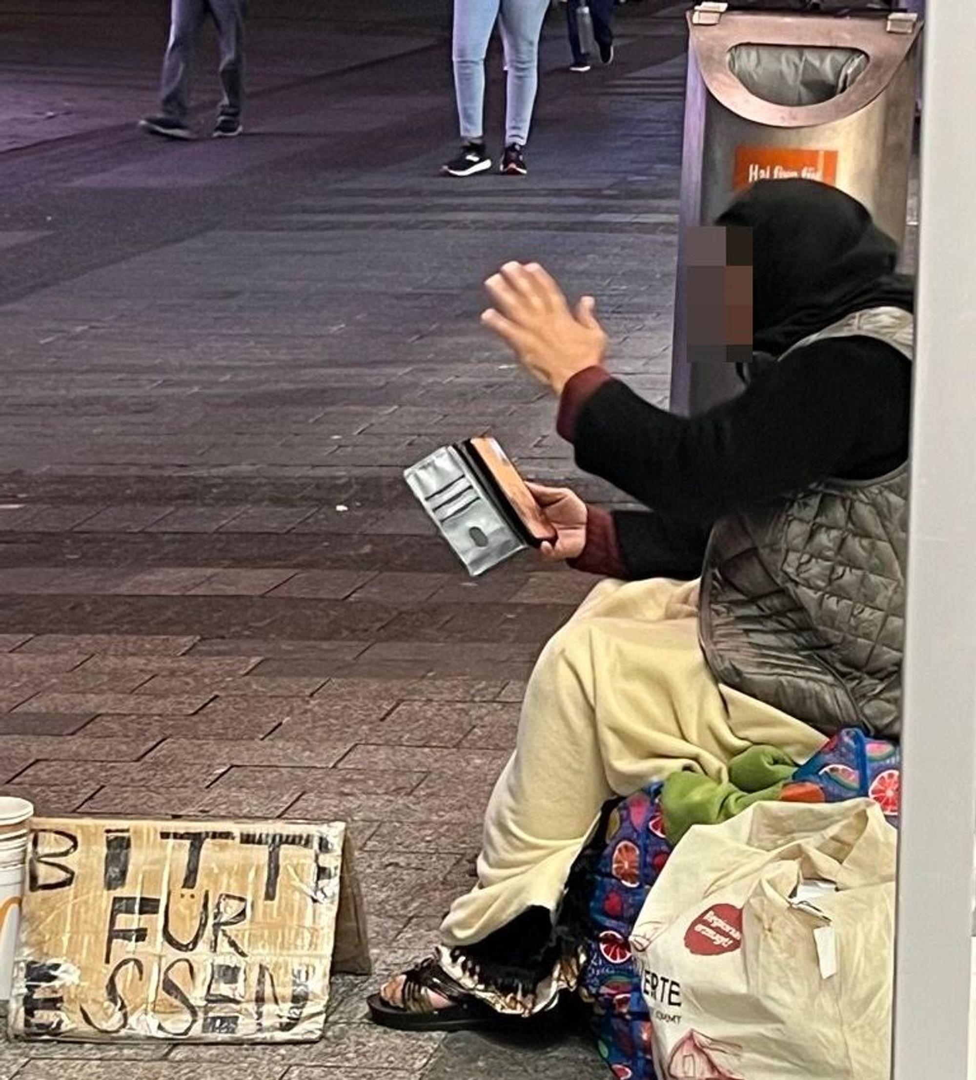 Eine Bettlerin sitzt auf einer Einkaufstasche in der Hohe Straße.