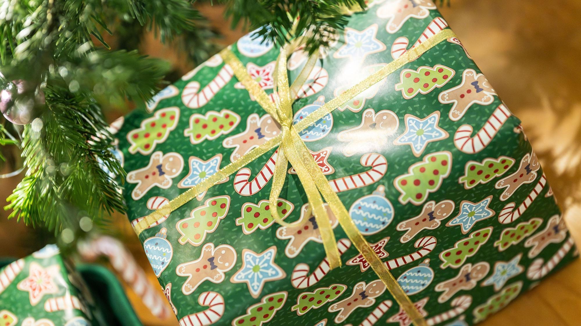 Geschenke liegen unter einem Christbaum in einer Wohnung.