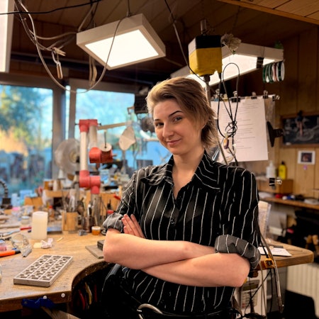 Eine junge Frau mit kurzen Haaren und gestreifter Bluse lächelt in die Kamera.