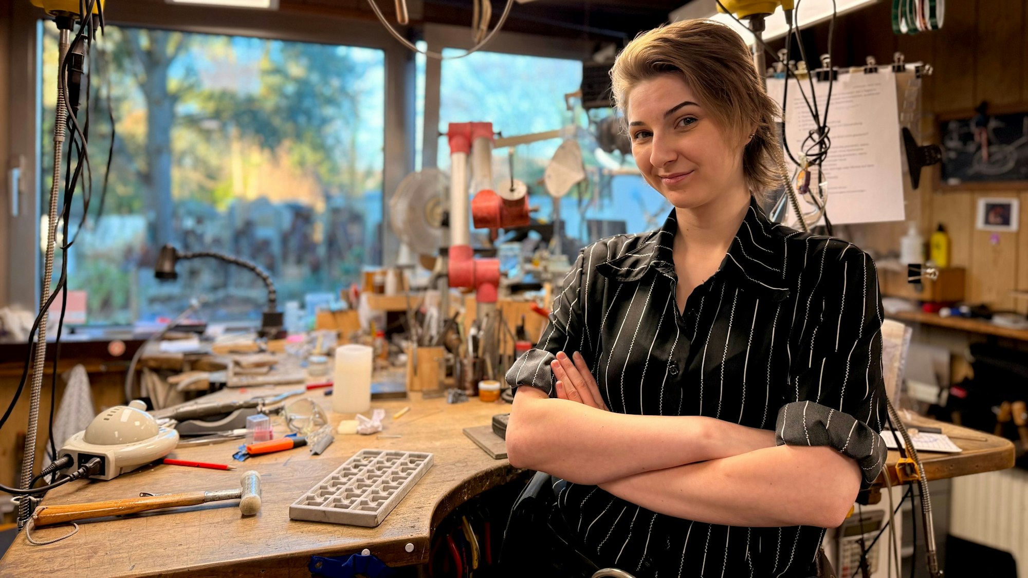 Eine junge Frau mit kurzen Haaren und gestreifter Bluse lächelt in die Kamera.