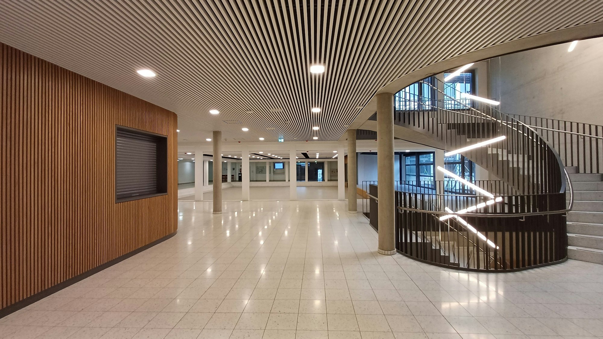 Ein leeres Foyer mit Treppen und glänzendem Boden.