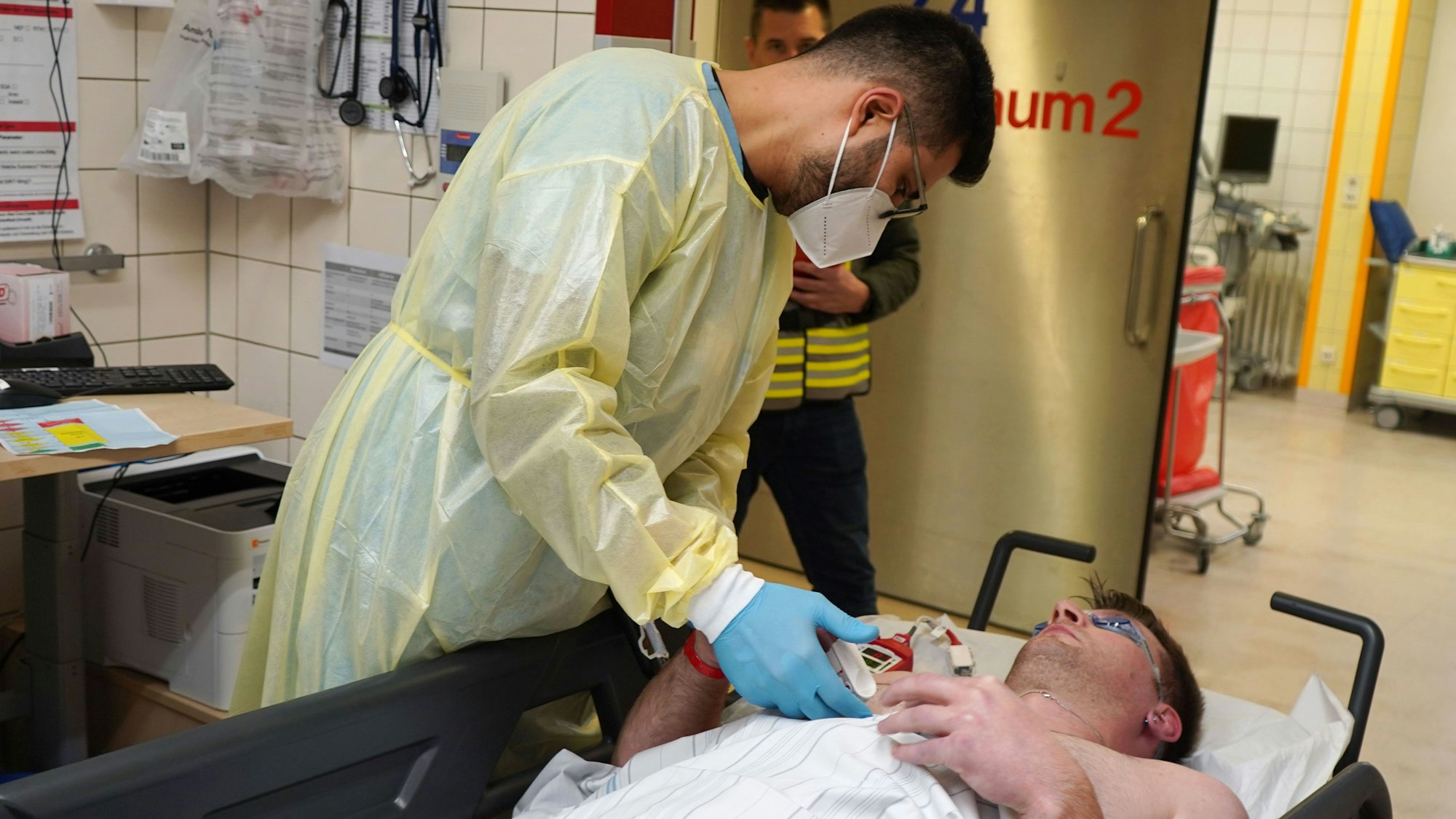 Ein Patient liegt auf einer Liege, während ein Krankenhaus Mitarbeiter über ihn gebeugt ist.