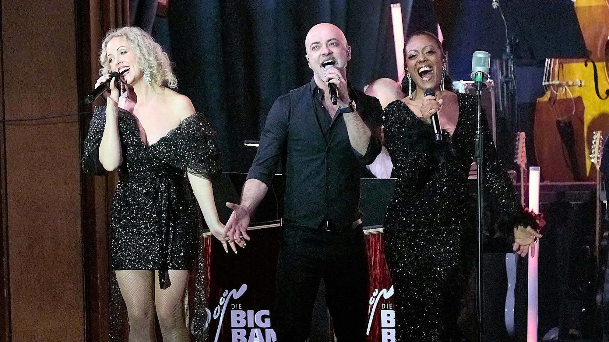 Die Sänger Sofia Andersson, Marco Matias und Bonita stehen auf einer Bühne und singen.