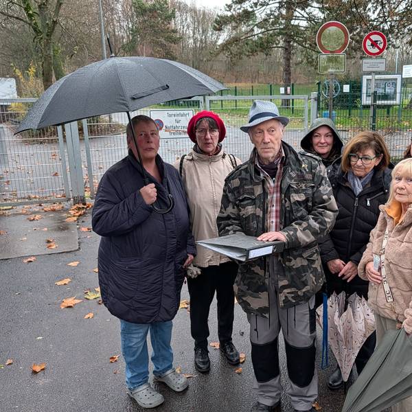 Das Foto zeigt eine Gruppe von Menschen mit einem Aktenordner vor dem Sportplatz in Efferen.