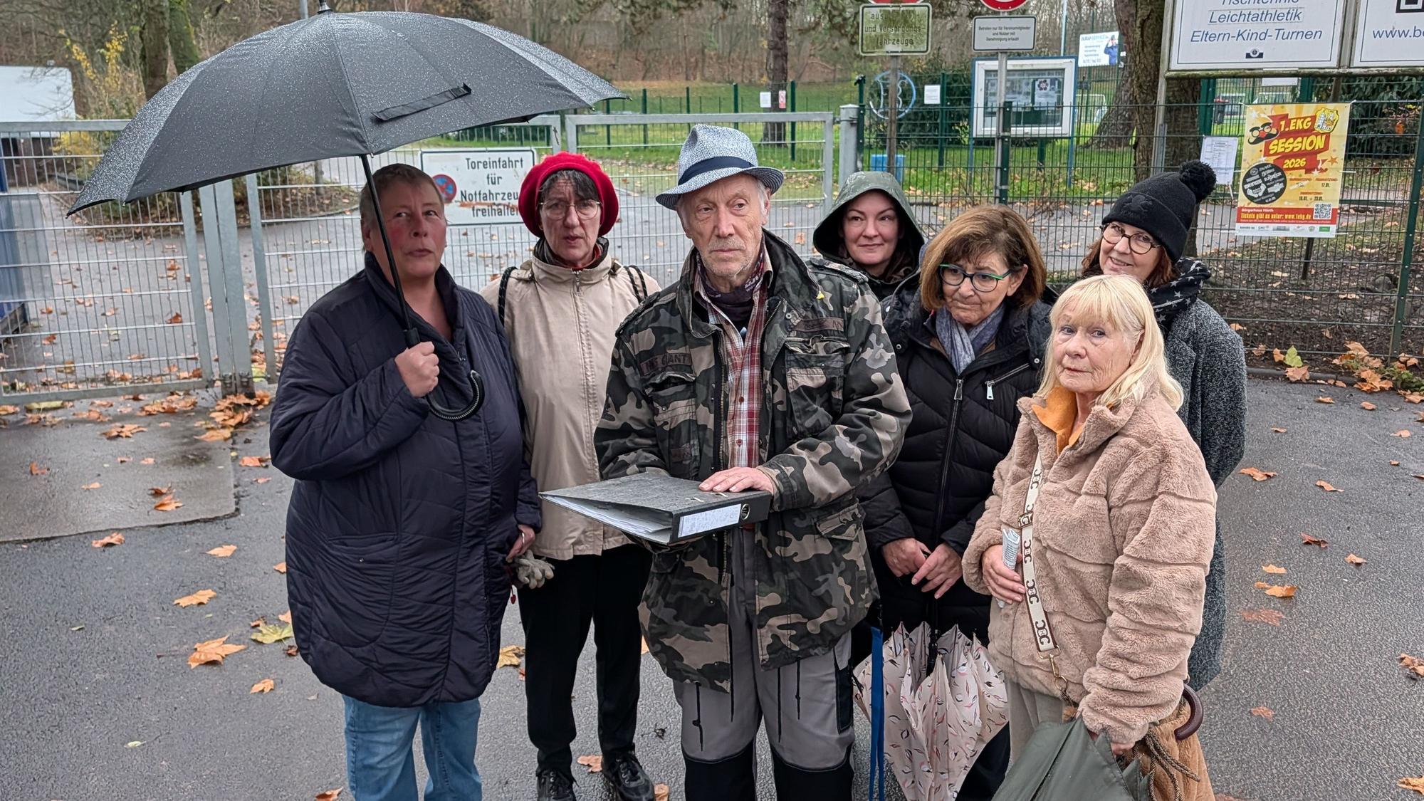 Das Foto zeigt eine Gruppe von Menschen mit einem Aktenordner vor dem Sportplatz in Efferen.