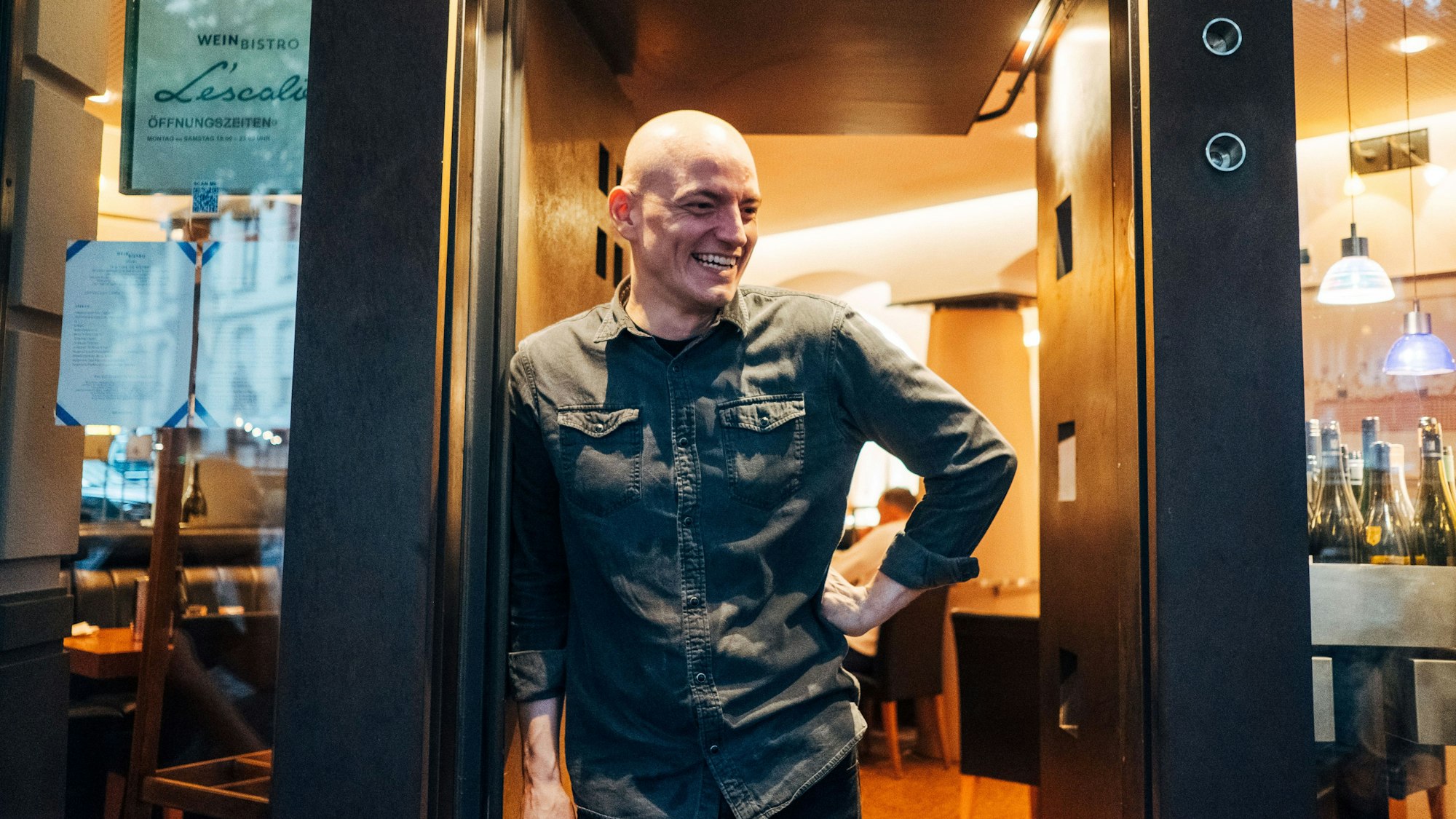 Ein Mann steht lächelnd in einem Türrahmen.